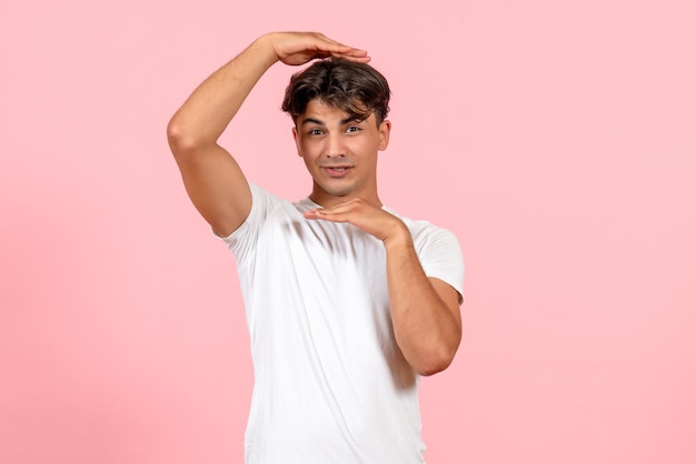 Vista frontale giovane maschio in maglietta bianca su sfondo rosa
