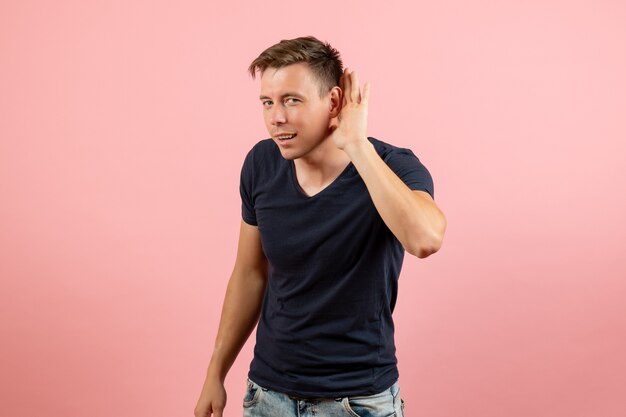 Vista frontale giovane maschio in maglietta blu ascoltando da vicino su sfondo rosa emozione maschile modello di colore umano
