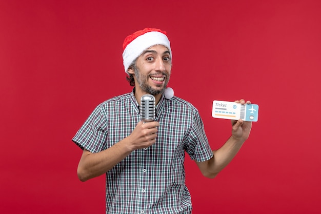 Vista frontale giovane maschio in possesso di biglietto e microfono su sfondo rosso
