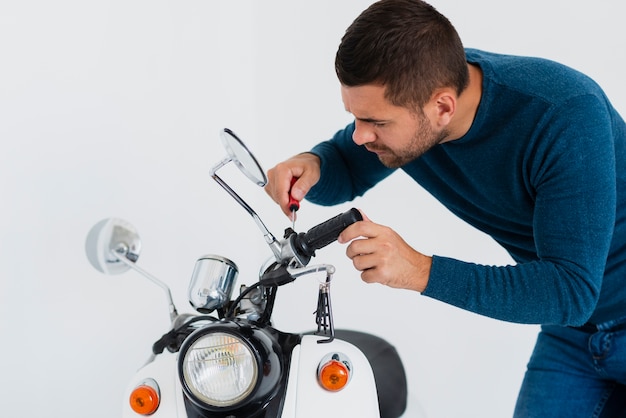 Vista frontale giovane uomo che ripara moto