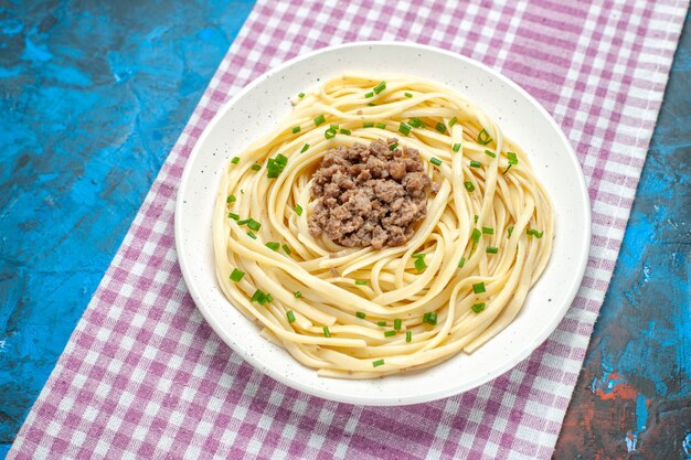 Vista frontale gustosa pasta italiana con carne macinata su cibo di farina di colore di pasta di carne di piatto blu