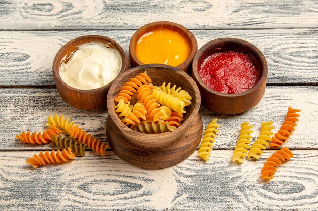 Vista frontale gustosa pasta italiana insolita pasta a spirale cotta sulla scrivania in legno grigio che cucina pasto piatto di pasta cena