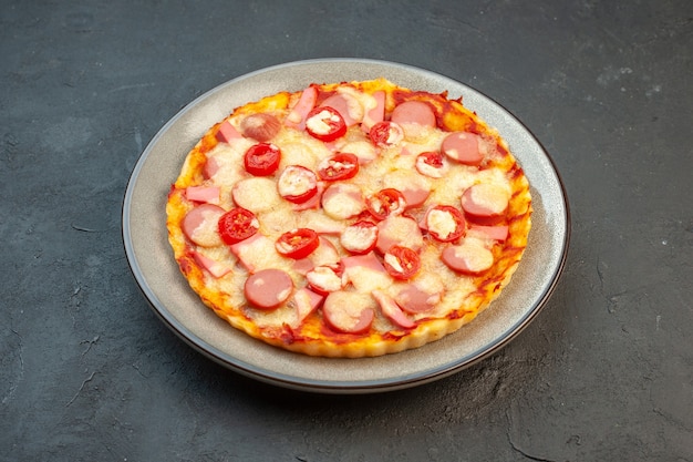 Vista frontale gustosa pizza al formaggio con salsicce e pomodori su sfondo scuro torta alimentare italiana fast-food foto pasta a colori