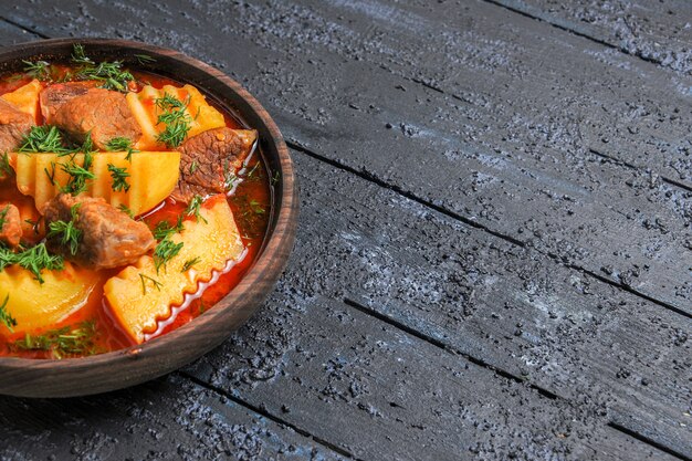 Vista frontale gustosa zuppa di carne con patate e verdure sul piatto di pasto al sugo di carne scuro scrivania