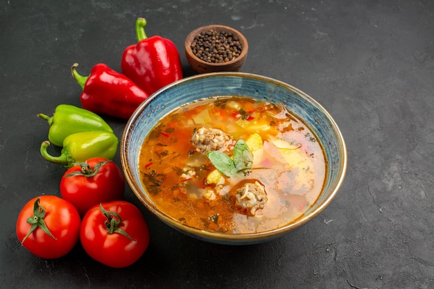 Vista frontale gustosa zuppa di carne con verdure fresche su uno sfondo scuro