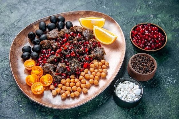 vista frontale gustose fette di carne fritte con fagioli uva e fette di limone all'interno della piastra su sfondo blu scuro