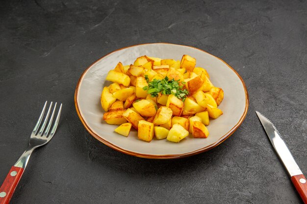 Vista frontale gustose patate fritte all'interno del piatto con verdure sulla scrivania scura