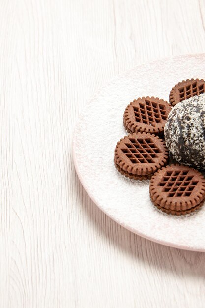 Vista frontale gustosi biscotti al cioccolato con piccola torta al cacao sulla scrivania bianca torta al cioccolato biscotti torta biscotto tè