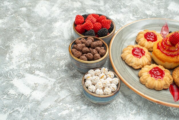 Vista frontale gustosi biscotti di sabbia con biscotti e caramelle su uno spazio bianco