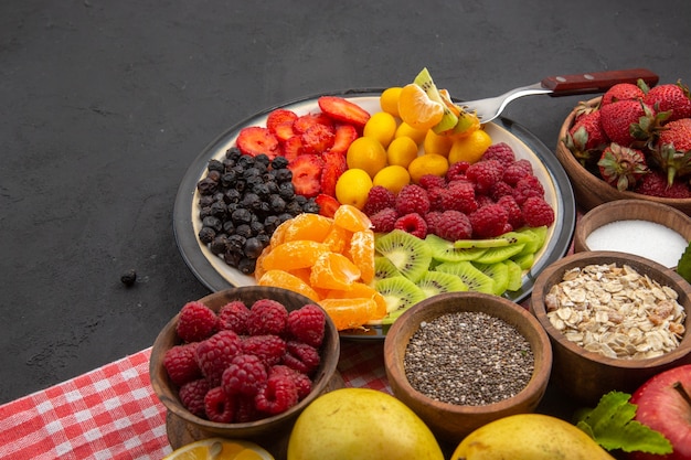 Vista frontale gustosi frutti a fette con bacche fresche e frutti su una vita sana di frutta tropicale dolce scura