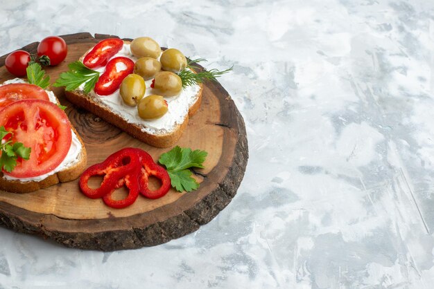 Vista frontale gustosi toast con pomodori e olive su tavola di legno sfondo bianco hamburger cena pane pasto panino orizzontale cibo