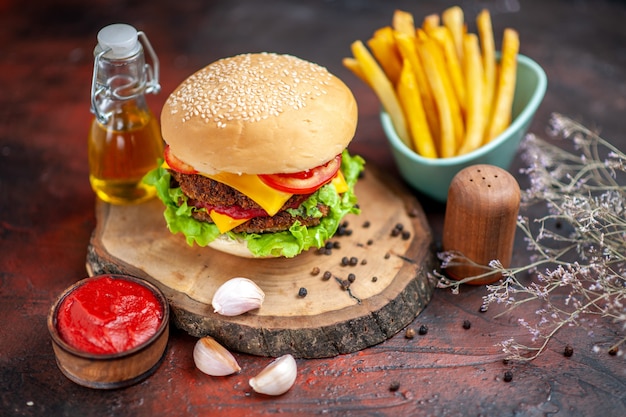 Vista frontale gustoso hamburger di carne con patatine fritte su sfondo scuro