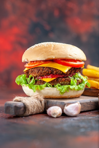 Vista frontale gustoso hamburger di carne con patatine fritte su sfondo scuro