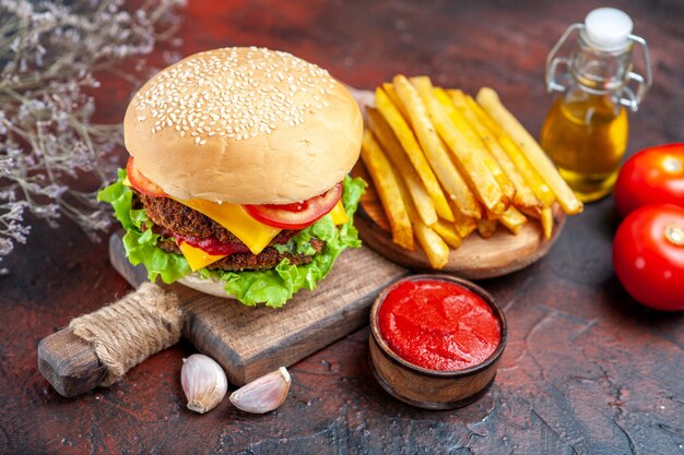 Vista frontale gustoso hamburger di carne con patatine fritte sul panino panino scuro scrivania fast-food