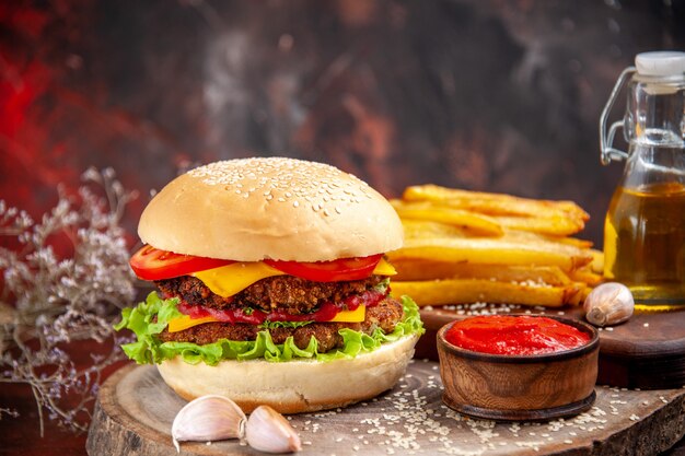 Vista frontale gustoso hamburger di carne con patatine fritte sul pavimento scuro