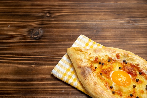 Vista frontale gustoso pane all'uovo appena sfornato sull'impasto marrone della scrivania cuocere il panino del pane