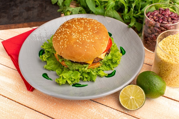 Vista frontale gustoso panino al pollo con insalata verde e verdure all'interno del piatto sullo scrittorio di crema di legno.