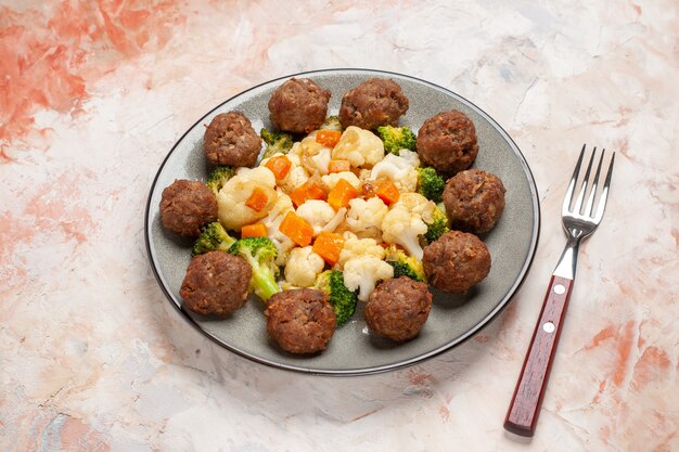 Vista frontale insalata di broccoli e cavolfiore e polpetta sul piatto una forchetta su sfondo nudo isolato