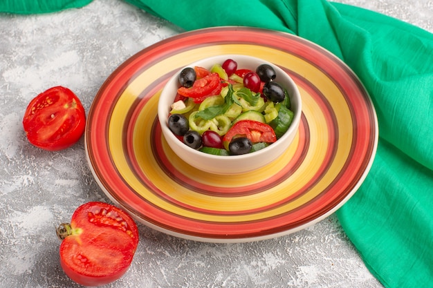 Vista frontale insalata di verdure fresche con cetrioli affettati pomodori oliva e formaggio bianco all'interno della piastra sulla superficie grigia cibo vegetale insalata pasto spuntino foto