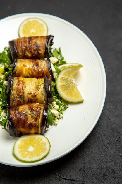 Vista frontale involtini salati di melanzane con fette di limone su una superficie scura che cucina cena piatto di olio di agrumi dinner