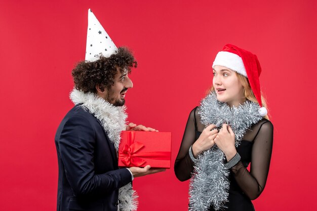 Vista frontale la giovane coppia lo scambio di regali di festa sul muro rosso emozione amore Natale