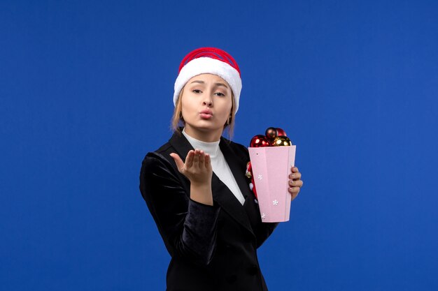 Vista frontale la giovane femmina che tiene i giocattoli dell'albero sul colore blu delle emozioni di festa del nuovo anno del fondo