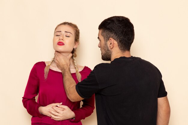 Vista frontale la giovane femmina in camicia rossa soffre di minacce fisiche e violenza sulla foto femminile dello spazio crema