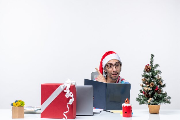 Vista frontale lavoratore maschio seduto nel suo posto di lavoro leggendo quaderno lavoro lavoro emozioni ufficio natale