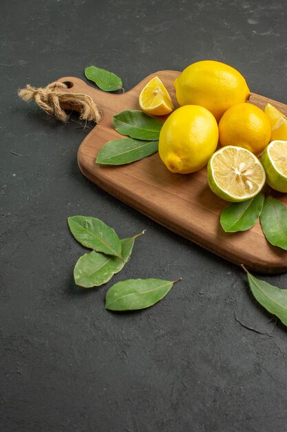 Vista frontale limoni gialli freschi frutti aspri su sfondo scuro