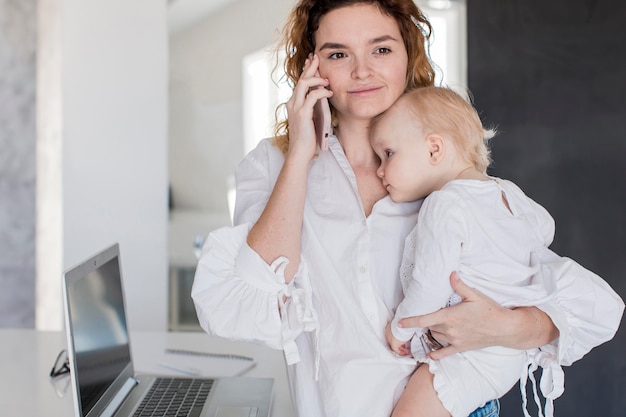 Vista frontale madre parla al telefono