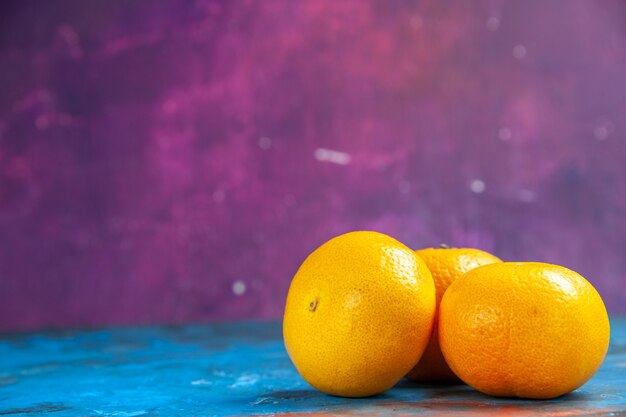 Vista frontale mandarini freschi sul tavolo blu-viola albero colore agrumi foto succo maturo
