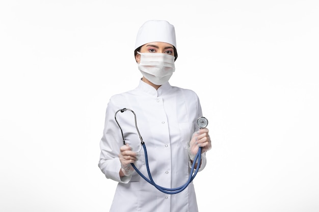 Vista frontale medico donna in tuta medica bianca sterile con maschera a causa di covid- sulla malattia del muro bianco covid- malattia da virus pandemico