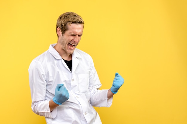 Vista frontale medico maschio gioire su sfondo giallo pandemia medica umana covid