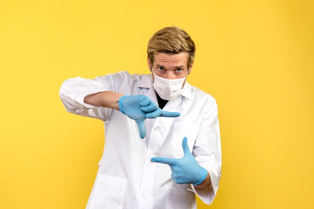 Vista frontale medico maschio su sfondo giallo pandemia medic salute covid-virus