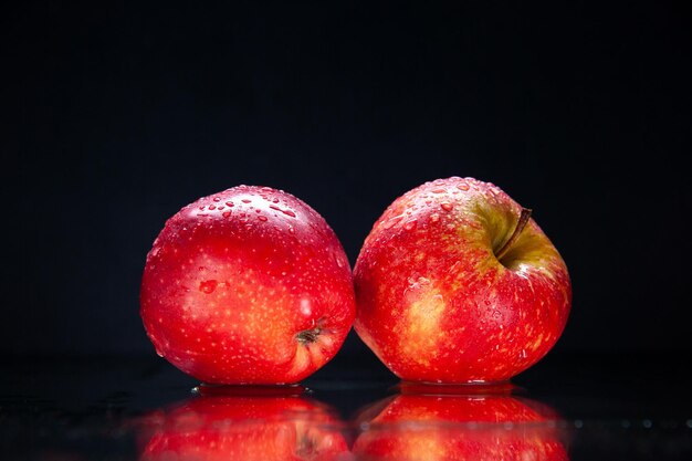 Vista frontale mela rossa fresca su sfondo nero colore maturi alberi dolci gustosa oscurità foto pera esotica