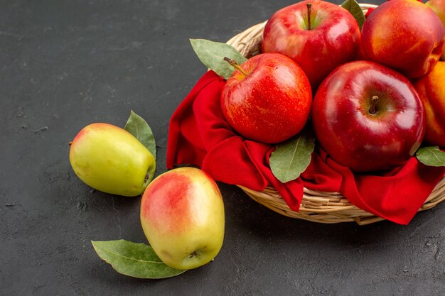 Vista frontale mele fresche con pesche sul tavolo scuro succo maturo di alberi da frutto