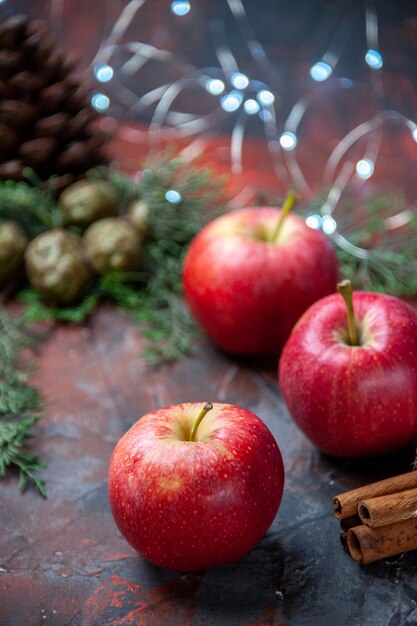 Vista frontale mele rosse bastoncini di cannella su sfondo scuro isolato