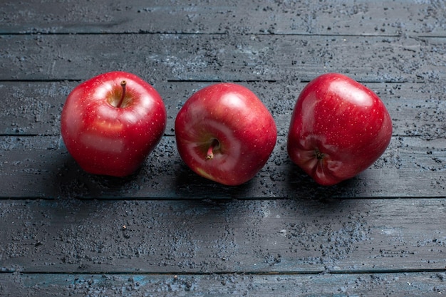 Vista frontale mele rosse fresche frutti maturi e morbidi sulla scrivania blu scuro molti alberi da frutto rosso pianta fresca colore fresh