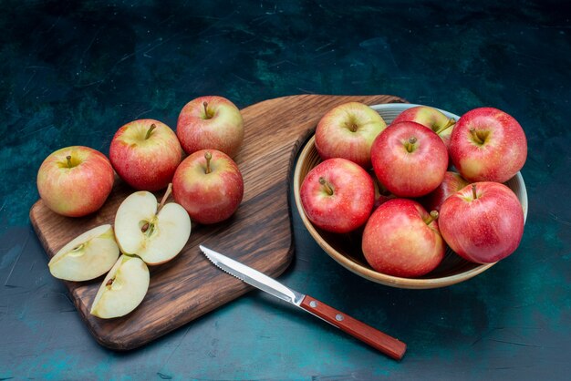 Vista frontale mele rosse fresche succose e pastose all'interno della piastra sulla superficie blu scuro frutta fresca matura pastosa
