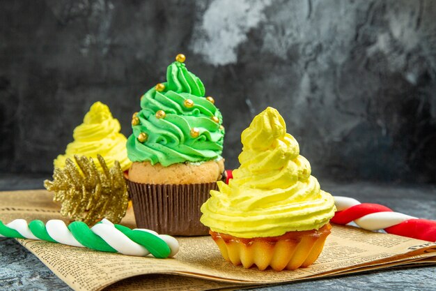 Vista frontale mini cupcakes ornamenti di natale caramelle di natale sul giornale al buio