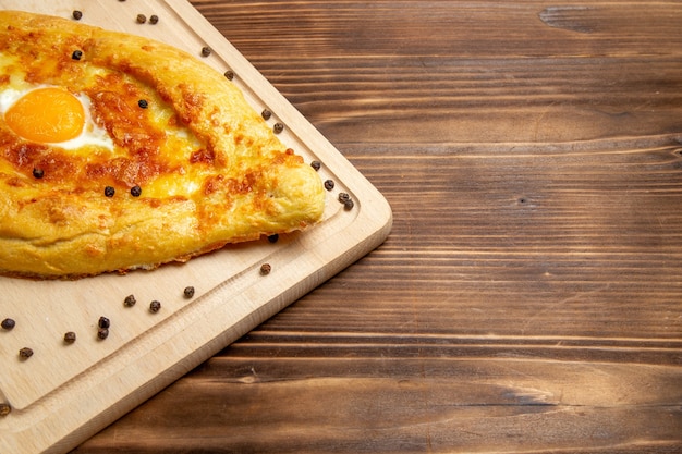 Vista frontale pane appena sfornato con uovo cotto sulla superficie rustica marrone cibo pasta colazione cuocere panino pasto