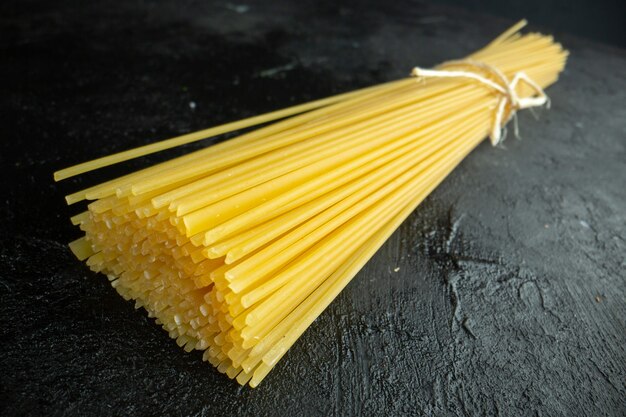 Vista frontale pasta italiana cruda lungamente formata su pasta scura colorante alimentare foto