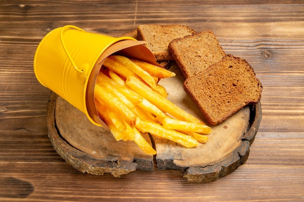 Vista frontale patatine fritte con pagnotte di pane scuro su pane marrone da scrivania con patate fast food