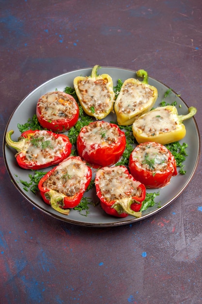 Vista frontale peperoni al forno con verdure al formaggio e carne all'interno del piatto sullo sfondo scuro cuocere il pasto del piatto della cena