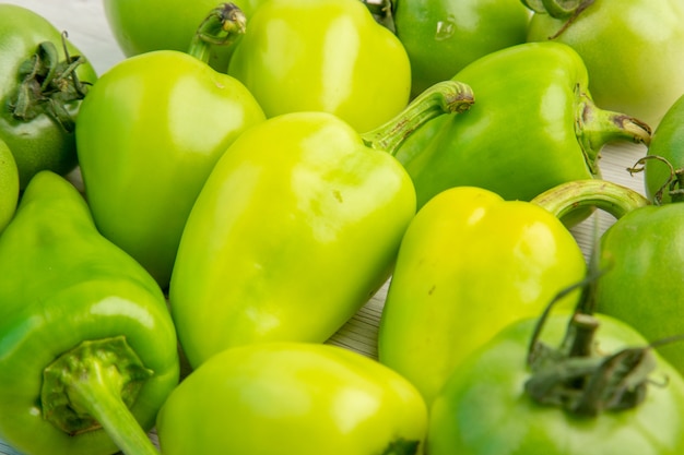 Vista frontale peperoni verdi con pomodori verdi su scrivania bianca colore insalata matura foto pasto dieta vita sana