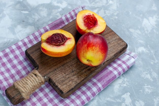 Vista frontale pesche fresche frutta pastosa e gustosa affettata sulla luce bianca scrivania