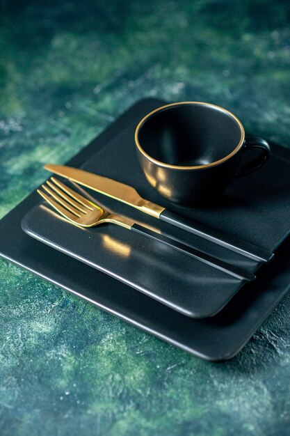 vista frontale piatti quadrati scuri con coltello forchetta d'oro e tazza su sfondo scuro