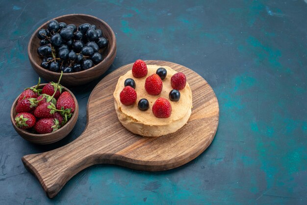 Vista frontale piccola torta al forno rotonda formata con fragole fresche sulla superficie blu scuro torta cuocere la torta di pasta di zucchero dolce