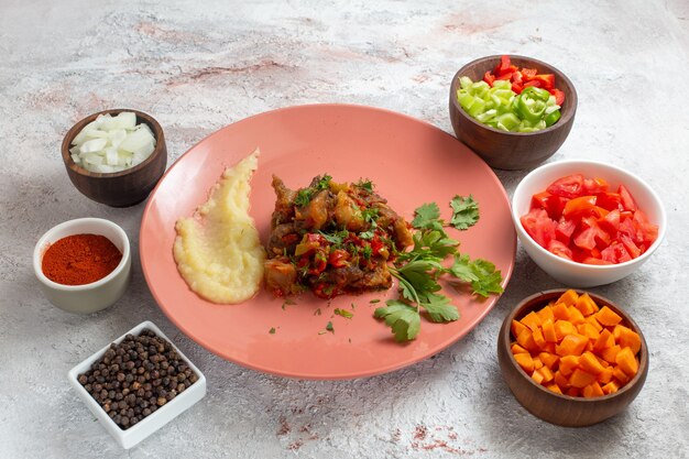 Vista frontale piccole fette di carne con insalata di peperoni a fette e condimenti sulla superficie bianca