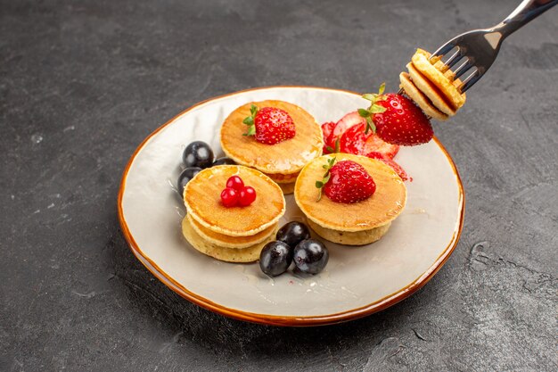 Vista frontale piccole frittelle gustose con frutta sulla frutta torta torta superficie grigia